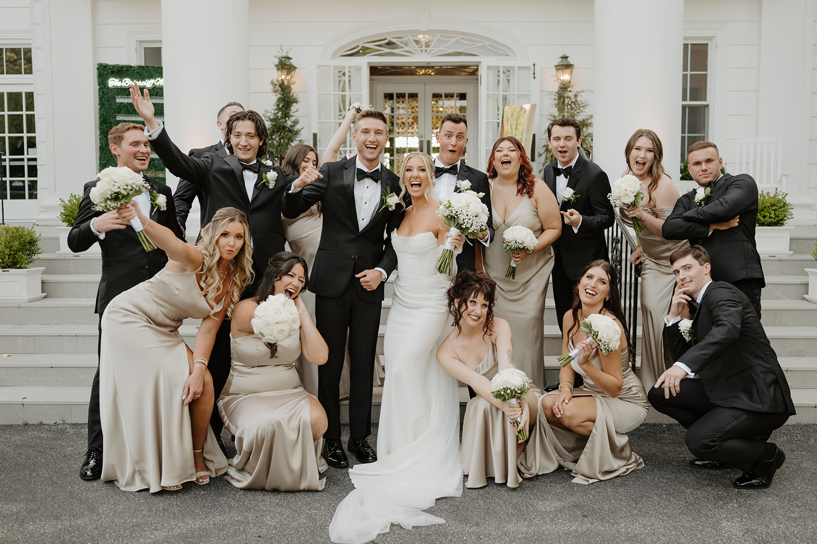 Wedding party makes fun, excited faces on the steps of the manor, celebrating the newlyweds.